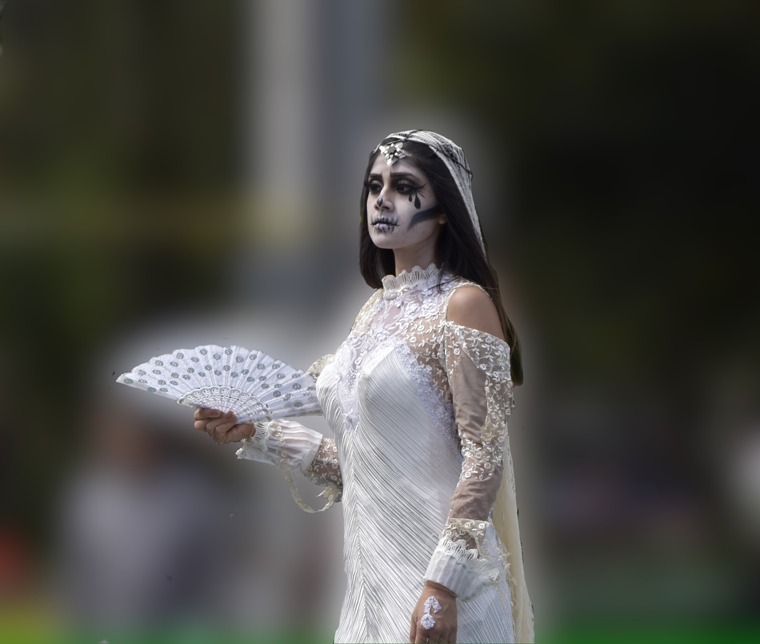 Mujer vestida de blanco con maquillaje de calavera representando a La Llorona en un desfile de Dia de Muertos en Orizaba, Veracruz
