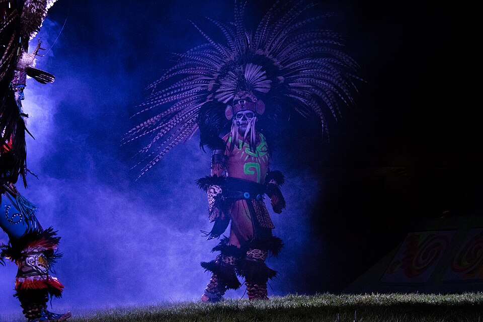 Danzante azteca con penacho durante el espectaculo nocturno de La Llorona en Xochimilco, envuelto en humo azul